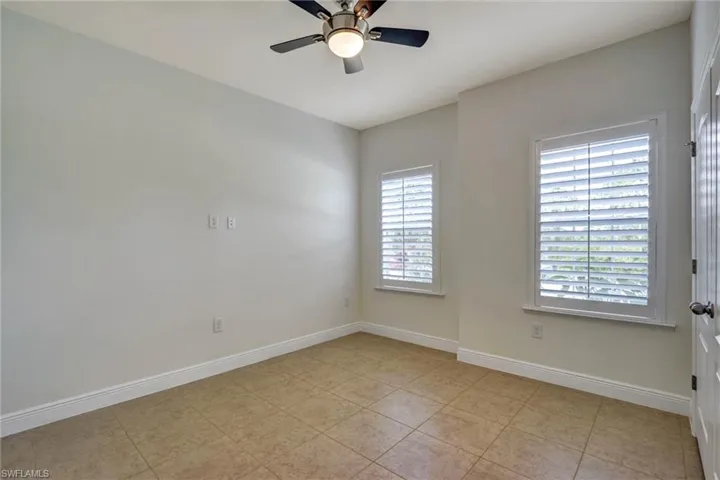 Room featuring neutral-toned tile flooring, light-colored walls, and a ceiling fan with integrated lighting