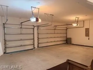Two-bay garage featuring concrete flooring, white painted walls, and two overhead garage door openers