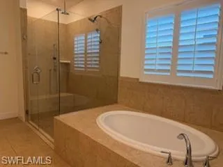 Built-in soaking tub with deck-mounted faucet, surrounded by floor-to-ceiling tile