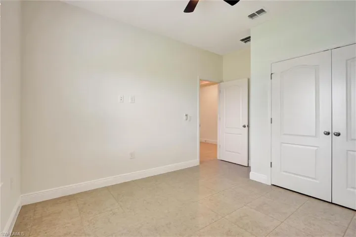 Neutral tone wall finishes, tile flooring, white baseboards, and a ceiling fan