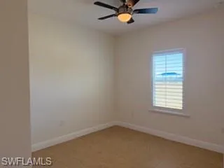 Interior room featuring light-toned walls, tile flooring, and a ceiling fan with integrated lighting