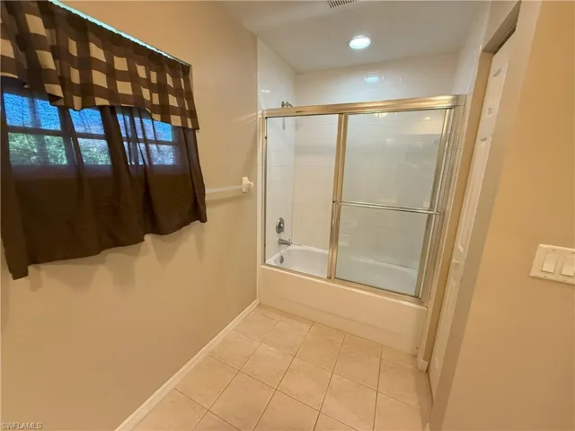 Bathroom featuring combined bath / shower with glass door, light tile patterned flooring, and recessed lighting