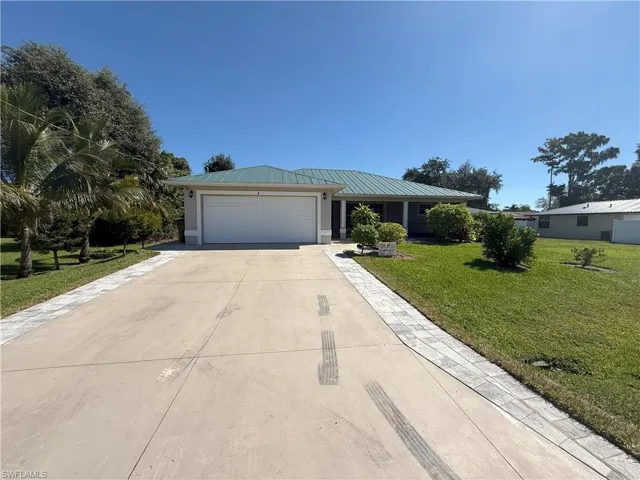 Ranch-style house with a front yard, driveway, a garage, and a metal roof