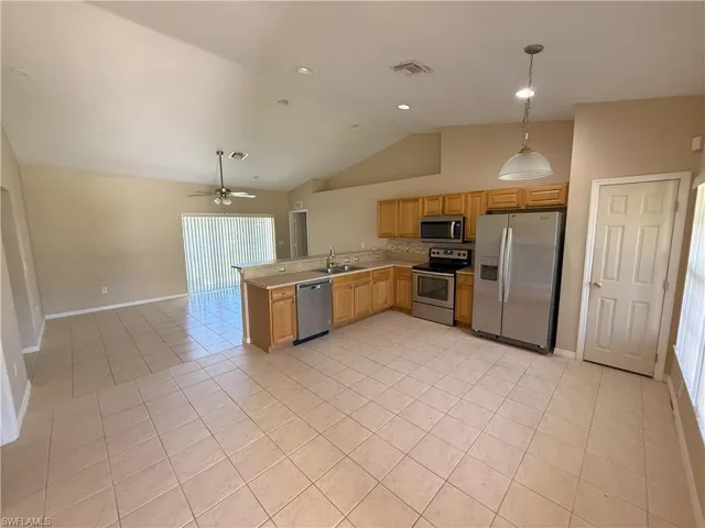 Kitchen featuring appliances with stainless steel finishes, light countertops, light tile patterned floors, hanging light fixtures, and open floor plan