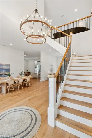 Staircase with a chandelier, wood finished floors, a high ceiling, recessed lighting, and baseboards