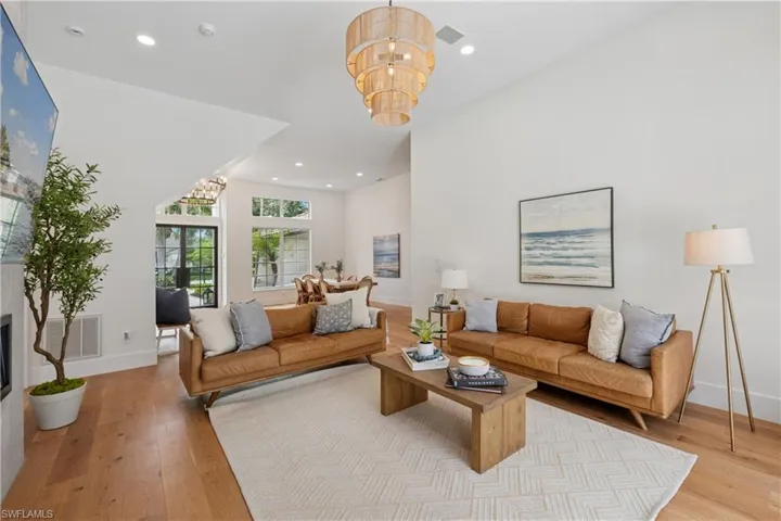 Living room featuring a chandelier, light wood finished floors, baseboards, recessed lighting, and a glass covered fireplace