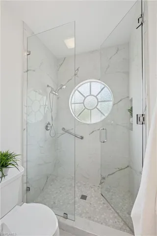 Full bath featuring toilet and a marble finish shower