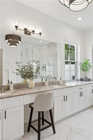 Bathroom featuring marble finish floors, a marble finish shower, double vanity, and recessed lighting