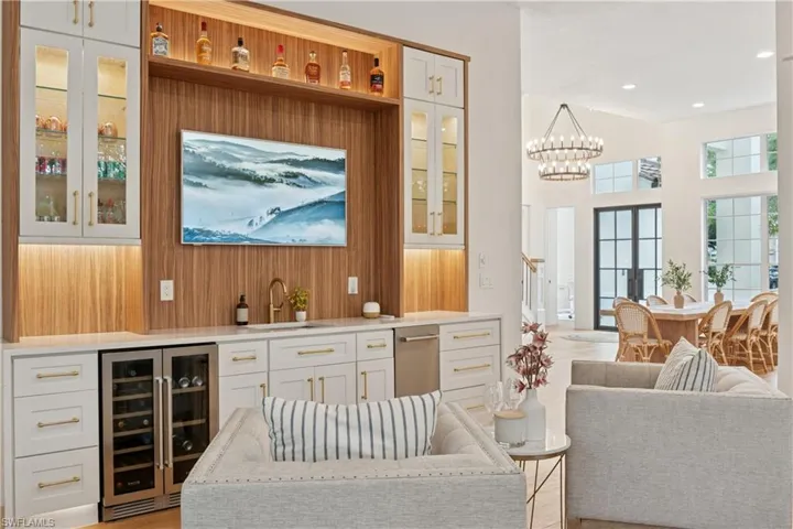 Indoor wet bar featuring wine cooler, a chandelier, wood walls, and recessed lighting