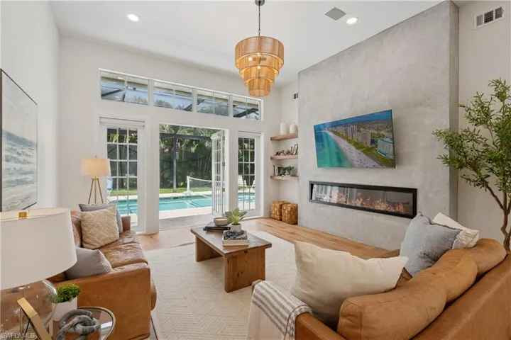 Living area with wood finished floors, recessed lighting, a fireplace, a towering ceiling, and a chandelier