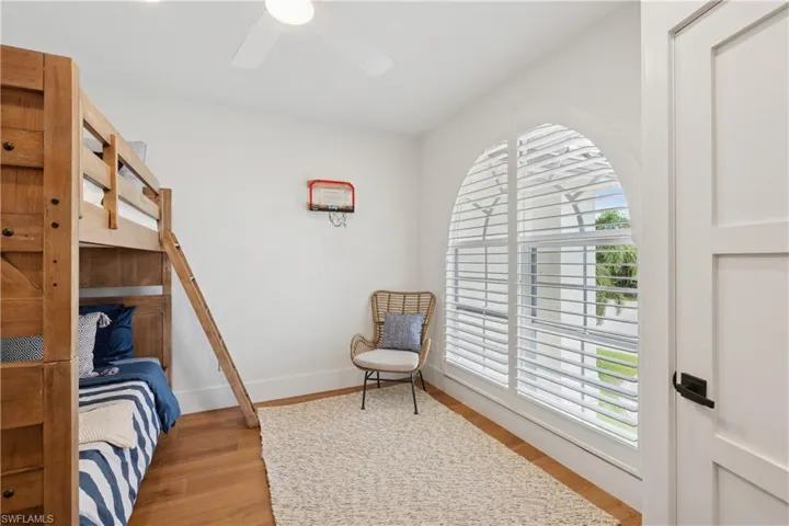 Bedroom with multiple windows, light wood finished floors, and baseboards