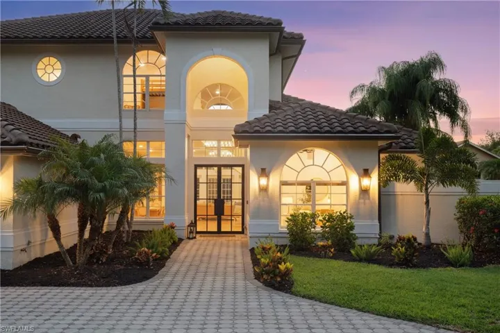View of front of house with french doors, a tiled roof, stucco siding, and a yard