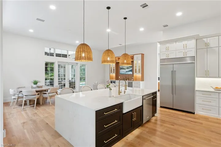 Kitchen with appliances with stainless steel finishes, a sink, light countertops, white cabinetry, and a kitchen island with sink