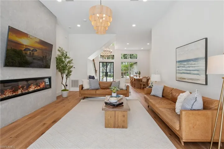 Living room with wood finished floors, a chandelier, recessed lighting, and a large fireplace