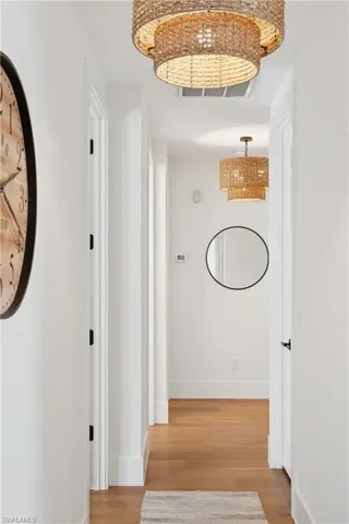 Hall featuring a chandelier, light wood finished floors, and baseboards