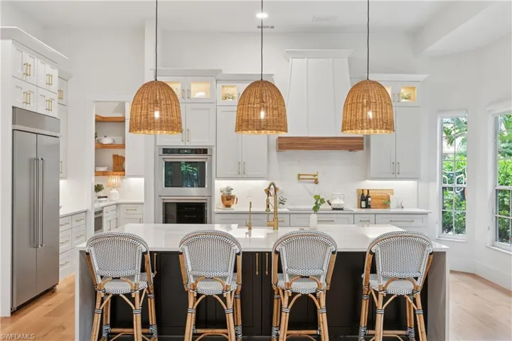 Kitchen with stainless steel appliances, light countertops, backsplash, and glass insert cabinets