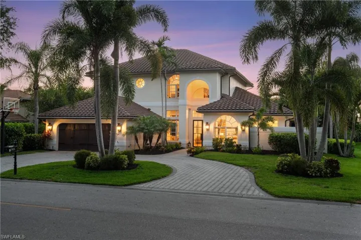 Mediterranean / spanish-style house with curved driveway, stucco siding, a front lawn, an attached garage, and a tiled roof