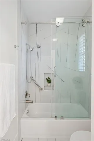 Bathroom featuring bath / shower combo with glass door and toilet