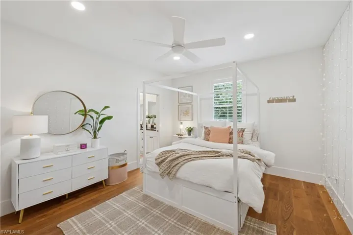 Bedroom featuring wood finished floors, recessed lighting, a ceiling fan, baseboards, and ensuite bathroom