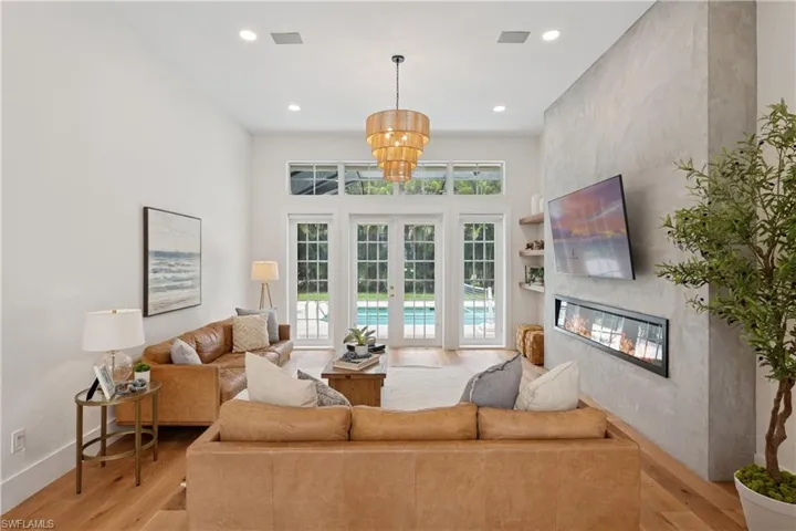 Living area with light wood finished floors, a fireplace, recessed lighting, and a chandelier