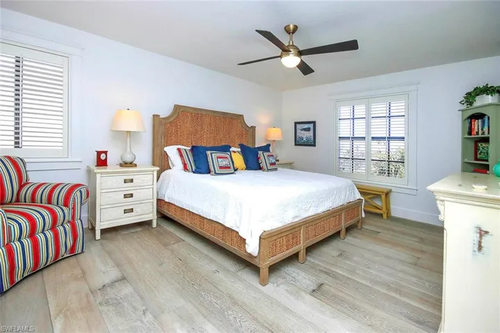 Bedroom with light wood-style flooring and a ceiling fan, coastal bright decor