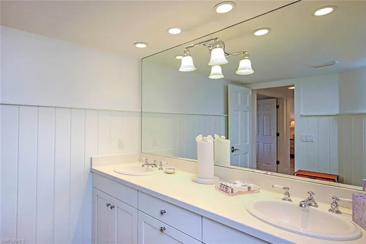 Full bathroom with double sinks, recessed lighting, wainscoting