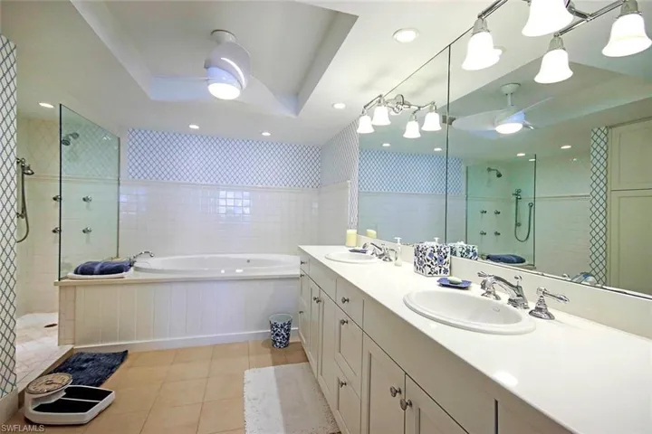 Bathroom with a tray ceiling, shower, a dual sinks, soaking tub and vintage wall paper