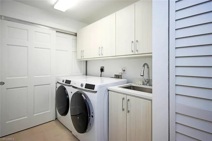 Laundry room with front loading washing machine and clothes dryer, cabinet space, and a sink broom closet