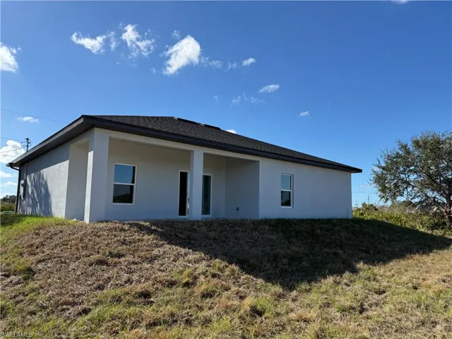 Rear view of property with stucco siding, a yard, and a patio area