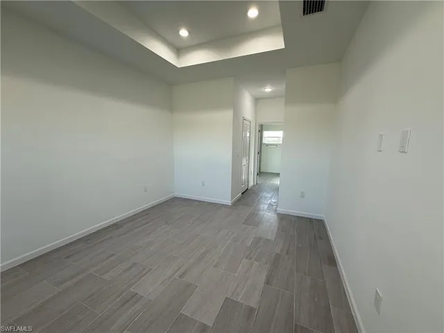 Unfurnished room with a raised ceiling, recessed lighting, and wood tiled floors
