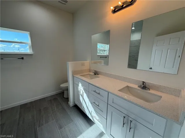 Bathroom featuring double vanity and baseboards