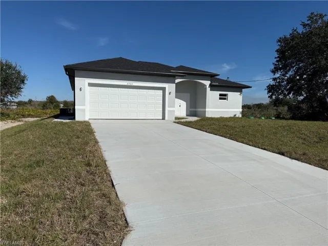 View of front of house featuring stucco siding, a front lawn, driveway, and a garage