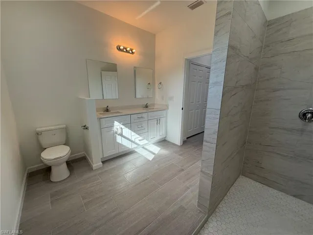 Full bathroom with double vanity and tiled shower