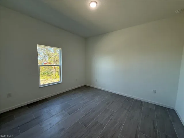 Spare room featuring baseboards and wood finish floors