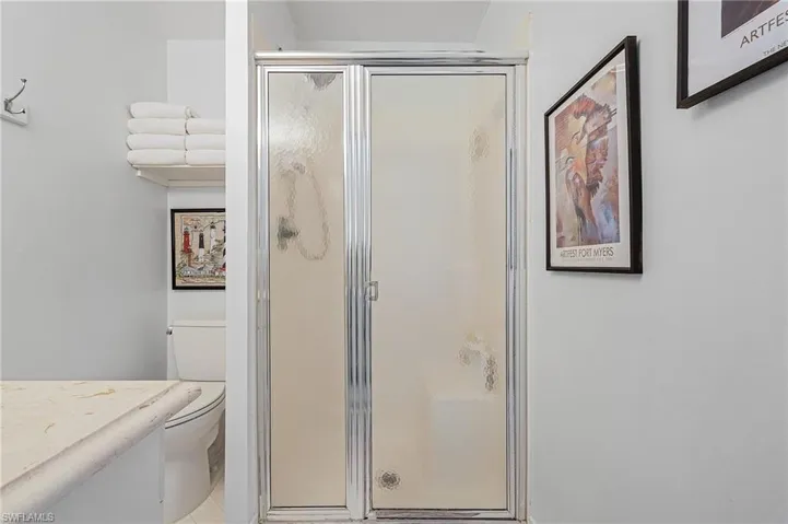 Bathroom featuring tile flooring, an enclosed shower, and toilet