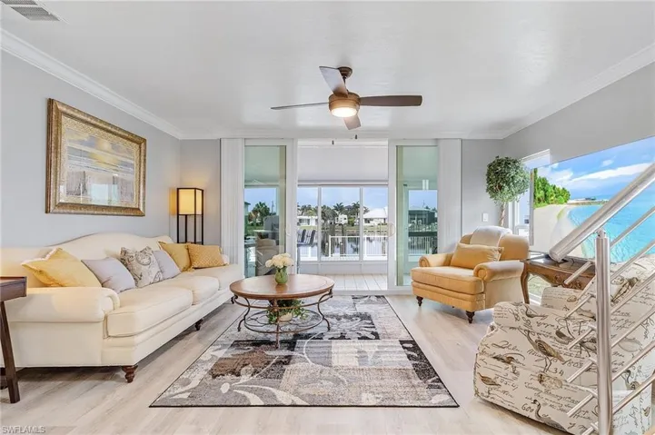 Living room featuring ceiling fan, light luxury vinyl flooring, and ornamental molding