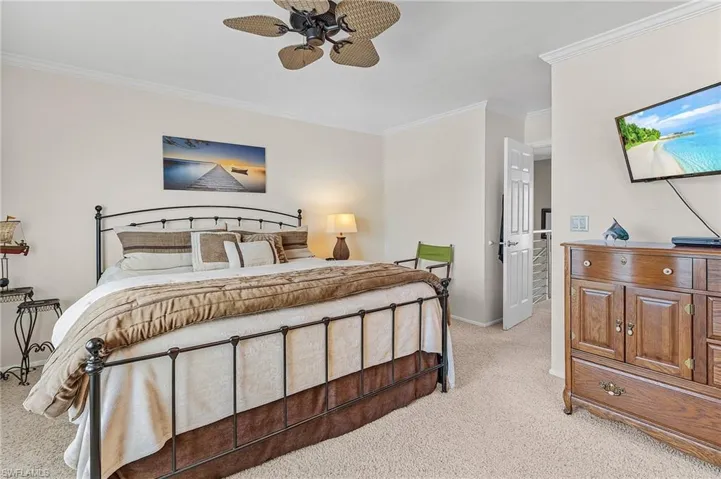 Carpeted bedroom with crown molding and ceiling fan