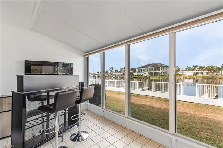 Sunroom / solarium featuring vaulted ceiling and a water view, Wall fire place and Bar