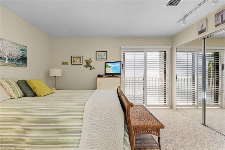 Carpeted bedroom featuring track lighting and multiple windows
