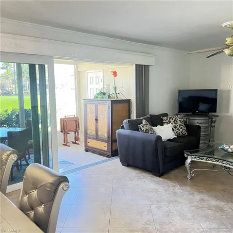 Living room featuring crown molding, light tile patterned floors, and ceiling fan