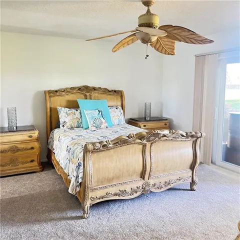 Bedroom with access to exterior, a textured ceiling, ceiling fan, and carpet