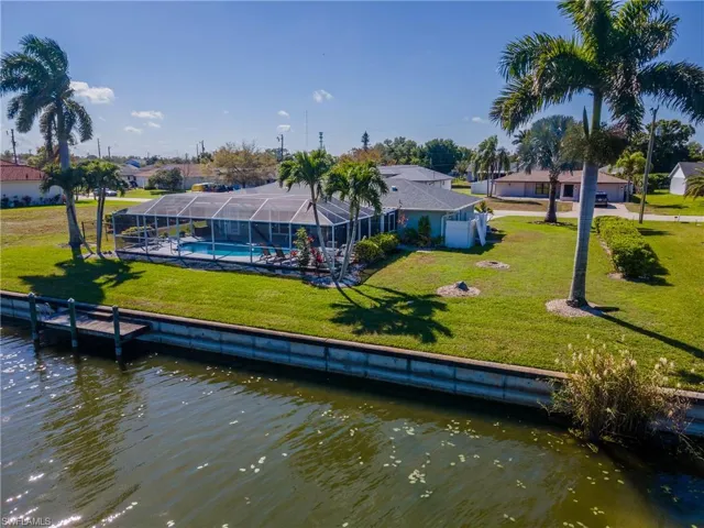 Back of property with a sunroom, a lanai, a water view, and an outdoor pool