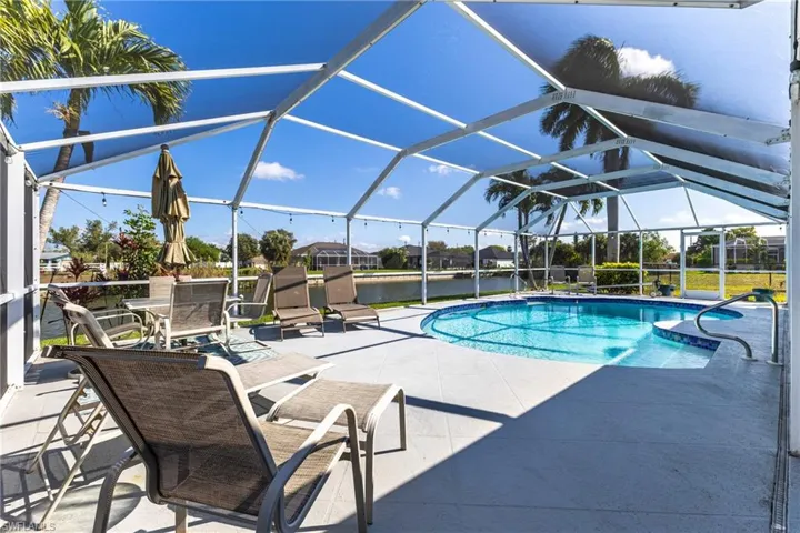 Swimming pool with a patio area, a sunroom, a lanai, a water view, and a residential view