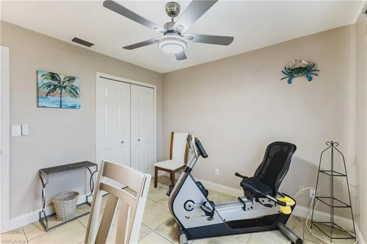 Exercise room with ceiling fan and light tile patterned flooring