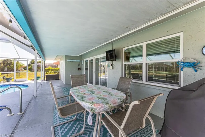 View of patio with an outdoor pool, glass enclosure, outdoor dining area, and a sunroom