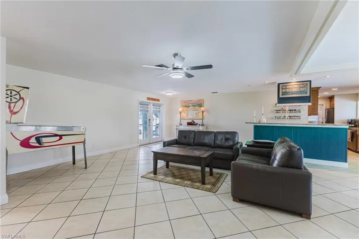 Living room with recessed lighting, a ceiling fan, light tile patterned floors, and french doors