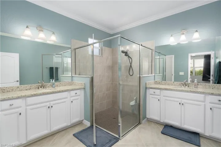 Bathroom featuring walk in shower, ornamental molding, tile patterned flooring, and vanity