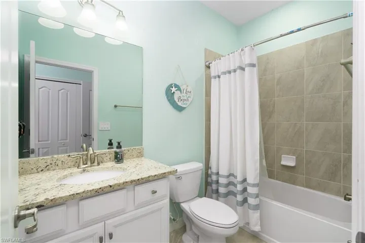Full bathroom featuring shower / bath combination with curtain, vanity, and toilet