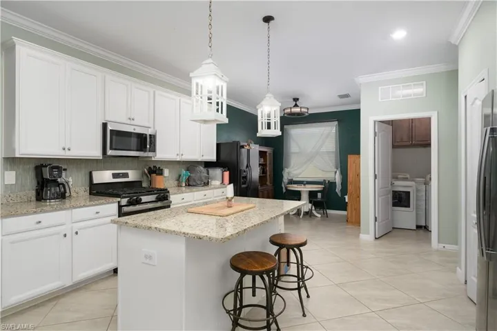 Kitchen featuring a kitchen island, appliances with stainless steel finishes, washer and dryer, and white cabinets