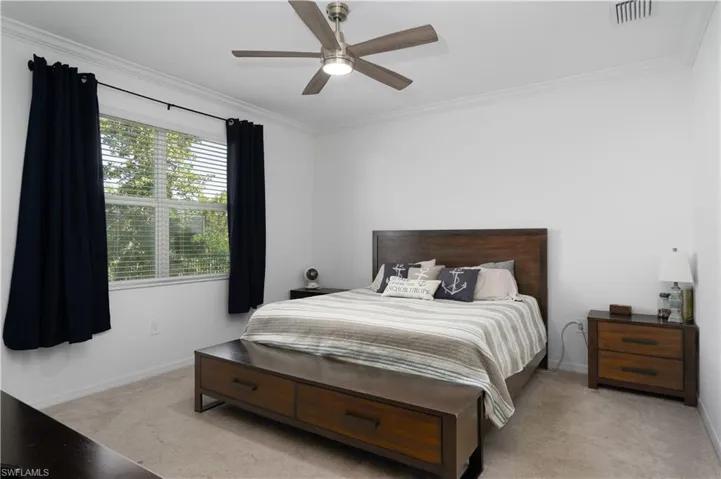 Bedroom with light carpet, crown molding, and ceiling fan